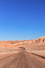 Fototapeta na wymiar Estrada no Deserto do Atacama, Chile, em meio a uma paisagem seca e céu azul ensolarado.