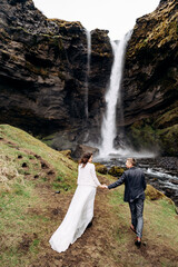 Destination Iceland wedding, near Kvernufoss waterfall. Wedding couple goes to the waterfall.