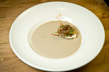 Cream-Soup of mushrooms with croutons and smoked fish. On a white plate. On rustic wooden background