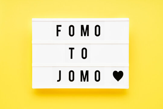 FOMO TO JOMO written in light box on yellow background. Choice, social problem concept. Top view