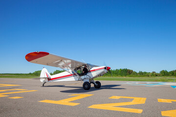 Pilot in small plane taxis toward runway for take off - Powered by Adobe