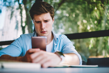 Fototapeta premium Thoughtful hipster blogger updating profile on telephone