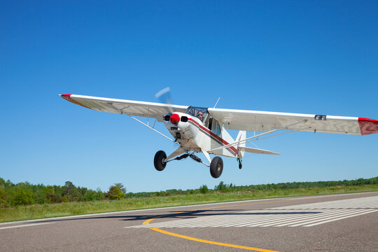 Small single engine airplane takes off from a municipal airfield in rural Minnesota