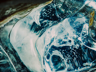 Close up of ice cube in a glass of alcohol coloured cocktail made by professional barista for...
