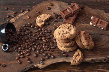 Piled up cookies, pieces of chocolate and coffe beans over a wooden board