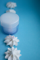Fototapeta na wymiar Beautiful blue cream jar with meringues on a blue background 