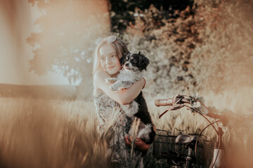 Junges Mädchen mit einem Hund auf dem Arm steht im Feld