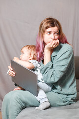 A young woman works at home with a tablet computer, along with a child.the son wants to communicate...