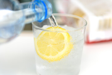 Pour sparkling mineral water into the glass with lemon.