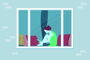 The girl is sitting at home and reading a book. View through the window. Cozy lounger near the window with pillows. Plastic window on a brick wall