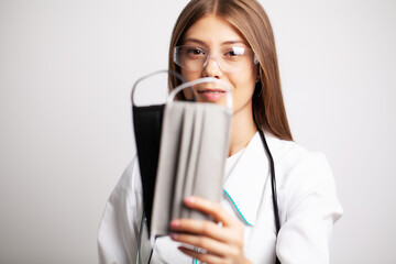 Young doctor woman in glasses holding a protective mask