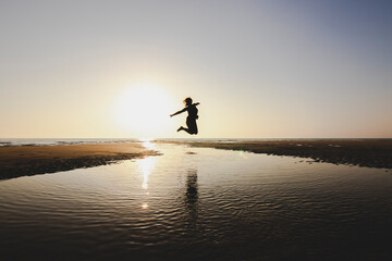 silueta de mujer saltando en la playa al atardecer