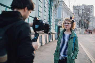 A girl makes a video blog with a cameraman on the street.