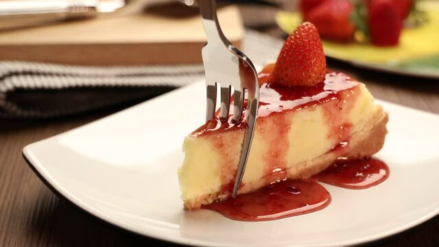 delicious slice of  strawberries cheesecake on a white plate on a wooden table