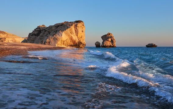 Sunset Aphrodites rock Romiou in Cyprus, Pafos Aphrodite rock Cyprus in soft evening light, curvy waves in the foreground touristic attraction of so called love rock