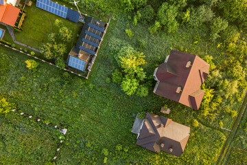 Aerial view of rural residential area with private homes between green fields at sunrise.