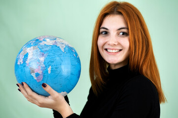 Portrait of a happy young woman holding geographic globe of the world in her hands. Travel destination and planet protection concept.