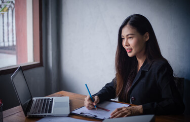 Asian businesswoman works passionately in a dimly-lit room, working from home after the coronary epidemic, or Corid-19. Until causing problems