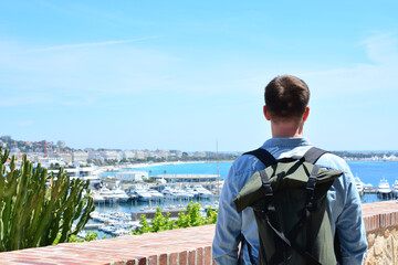 Young man with backpack in the city of Cannes in France enjoying the view of the French Riviera. Lifestyle and back to travel concept. Back to normal life after pandemic. Quarantine is over.