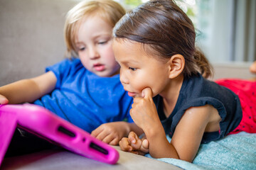 Caucasian boy and Asian girl play and learn on electronic  tablet device