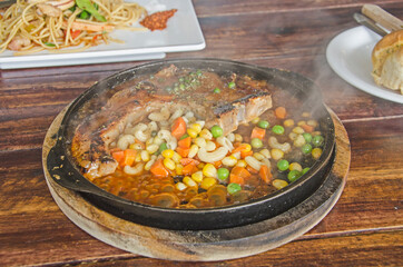 Pork chop steak serves in hot black pan