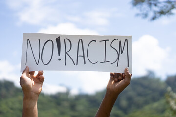 No rasicm End rasicm.Crowd of protesters people on street.black woman raised hands showing sig...