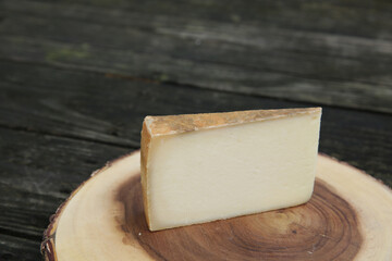 parmesan cheese on a wooden plate on a wooden table. Organic dairy product concept. With copy space for text or image.