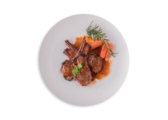 lamb steak on white plate, Rack of Lamb (ribs) with Rosemary garlic dressing, garnished with baby carrots, potatoes, and rosemary sprigs.