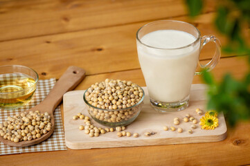 Soy milk in glass and soy bean on spoon it on wooden table background, healthy concept
