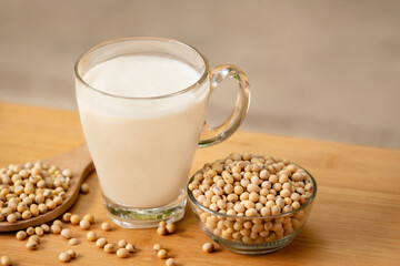 Soy milk in glass and soy bean on spoon it on wooden table background, healthy concept
