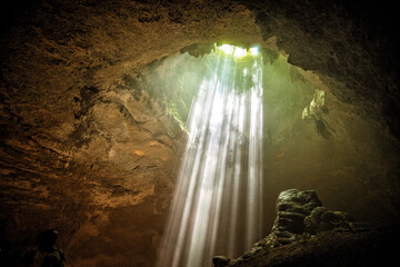 rays of light shine through at Jomblang cave near Yogyakarta, Indonesia - Powered by Adobe