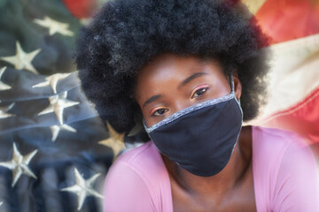 A portrait of a beautiful black girl wearing face masks with the USA flag on the background.