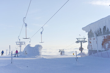 At the top of ski lifts as they rise above the clouds, covered in snow.
