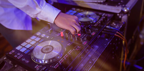 Obraz premium DJ mixing outdoor at beach party festival with crowd of people in background - Summer nightlife view of disco club outside - Soft focus on hand fingers - Fun ,youth,entertainment and fest concept