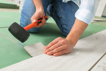 Carpenter installing laminate flooring in room