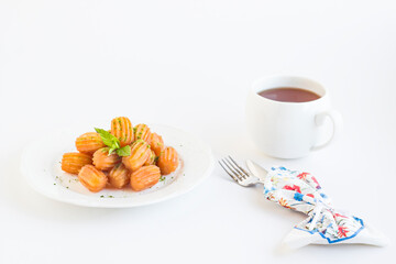 Traditional Turkish Pastry Dessert,Tulumba in the white porcelain plate with a cup of tea.Garnished with pistachio powder.
