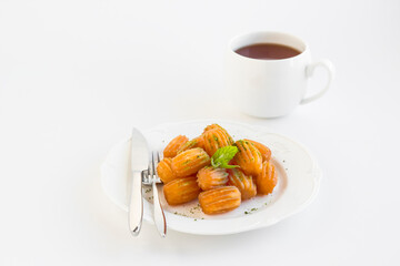 Traditional Turkish Pastry Dessert,Tulumba in the white porcelain plate with a cup of tea.Garnished with pistachio powder.