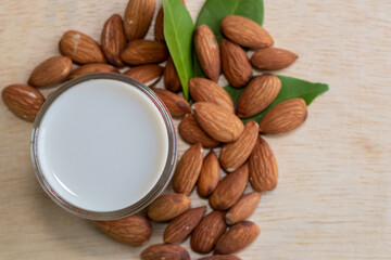 Almond milk in glass with almonds on wooden table