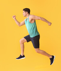 Sporty running young man on color background