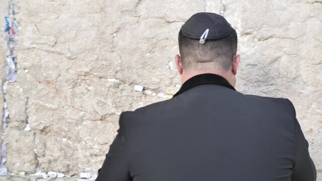 Jew puts note to God, kiss and touch the Western Wall with respect and devotion