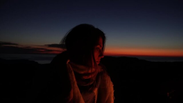 Young girl alone in dark woods alone by campfire