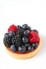 French dessert. Berry tart decorated with organic fresh blueberries, raspberries and blackberries. White background. Back view. 
