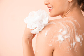 Beautiful young woman taking shower on color background