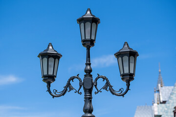 Fototapeta na wymiar Retro street lamppost against the blue sky background, closeup