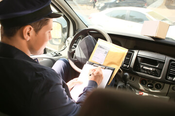 Handsome young postman in car