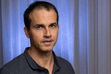 44 year old mature man with blue curtain background (flash with blue filter).