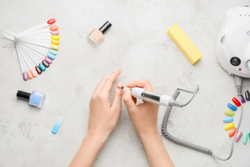 Female hands with supplies for manicure on light background