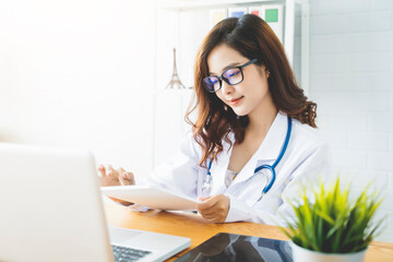 Medical health clinic beautiful Asian doctor working using smart tablet touching, stethoscope diagnosing patient analysis research examination healthcare provider service insurance in modern office