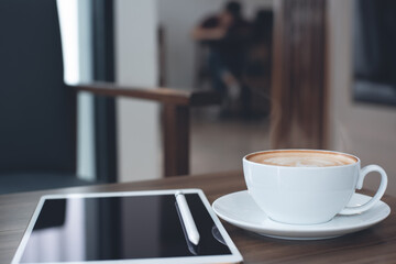 Cup of coffee and digital tablet on table in coffee shop