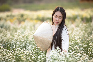 A beautiful Vietnamese woman is walking to see the flowers blooming in the garden.